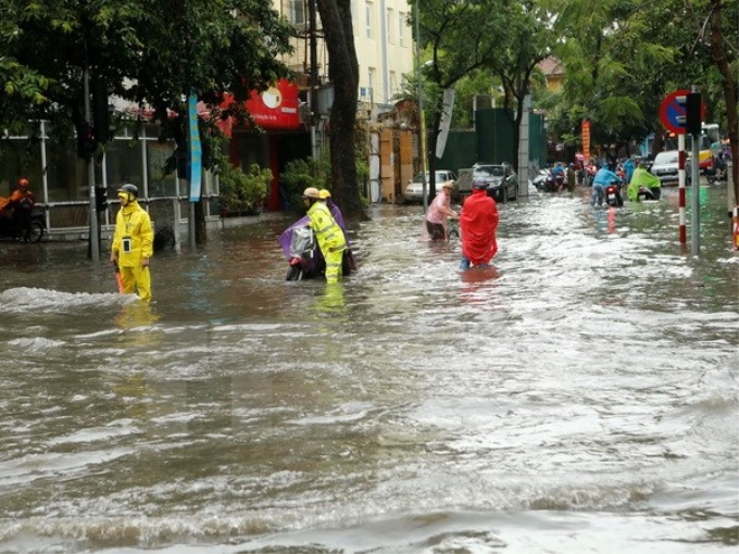 Cảnh sát giao thông Hà Nội giúp dân vượt qua chỗ ngập tại phố Lý Thường Kiệt-Phan Bộ Châu. (Ảnh: Doãn Tấn/TTXVN)